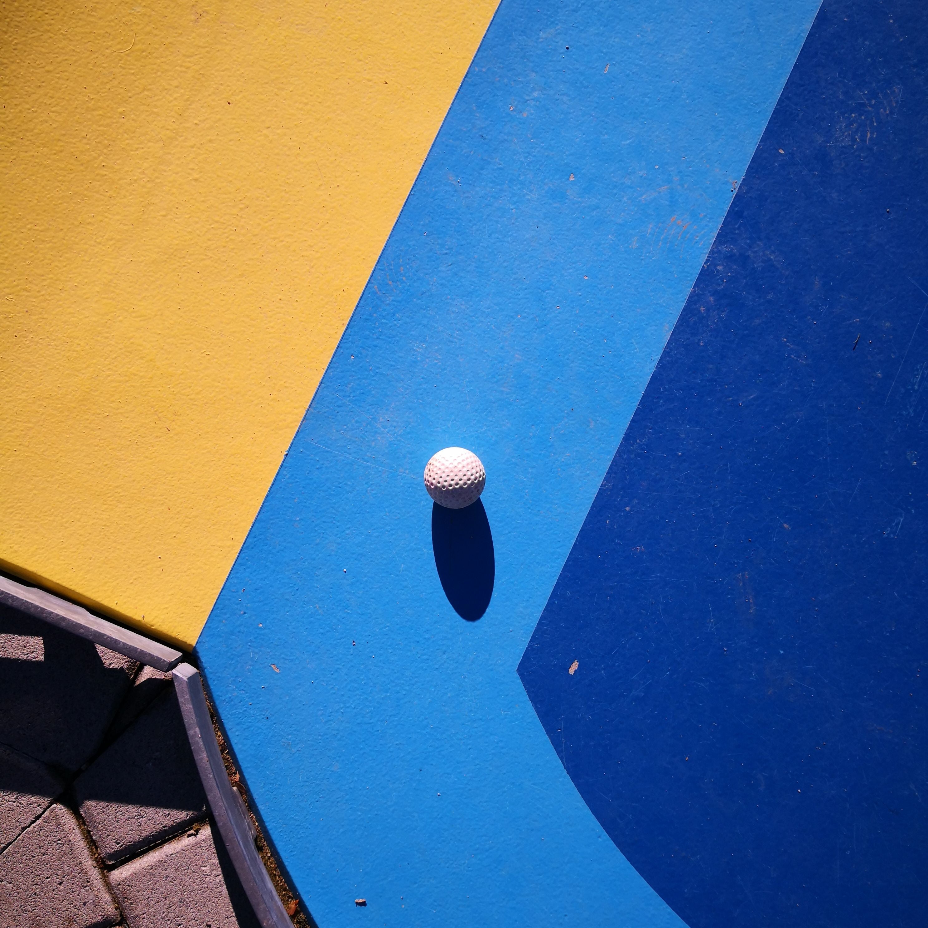 White golf ball on a blue and yellow surface
